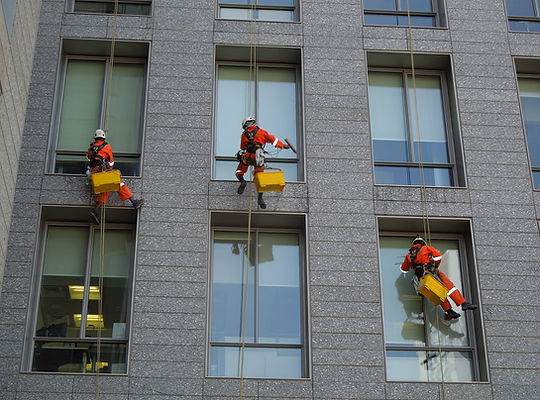 промышленные альпинисты моют окна в доме